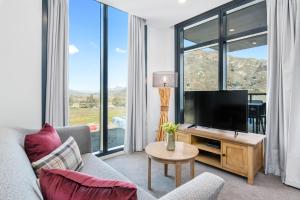 a living room with a television and large windows at Kawarau View in Queenstown