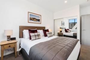 Un dormitorio con una cama grande y una mesa con una lámpara. en Kawarau View en Queenstown