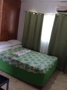a small bed with green curtains and towels on it at Troy Lodge in Basco