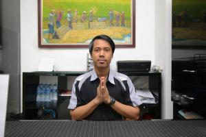 Un hombre está sentado en una oficina con las manos delante. en Residence100, en Yakarta