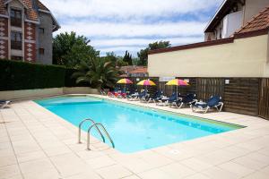 a swimming pool with chairs and umbrellas next to a building at Hôtel Le Dauphin in Arcachon