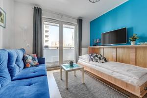 a blue living room with a couch and a tv at Platinium Spectrum Apartment in Gdańsk