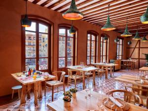 un restaurante con mesas y sillas de madera y ventanas en Hotel Boutique Adolfo, en Toledo