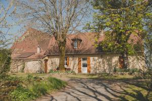 uma casa de pedra com uma árvore em frente em La ferme de Bousserand em Pontours