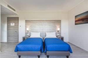 a bedroom with two beds with blue sheets and two tables at Country House Campofiore in Pontelongo