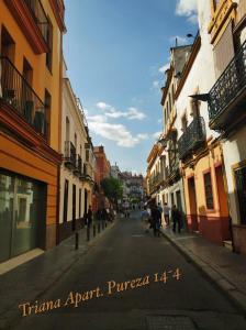 eine Stadtstraße mit Gebäuden und Menschen, die die Straße hinuntergehen in der Unterkunft TRIANA PUREZA 12-14 in Sevilla