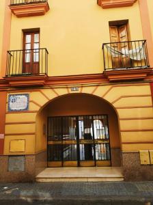 einen Eingang zu einem Gebäude mit einer Tür und Fenstern in der Unterkunft TRIANA PUREZA 12-14 in Sevilla