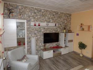 ein Wohnzimmer mit einer Steinmauer und einem TV in der Unterkunft Ferienwohnung Fräbel in Asbach