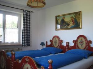 a bedroom with three beds and a painting on the wall at Gästehaus Alpenland in Halblech