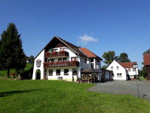 un grande edificio bianco con un orologio sopra di Gasthof Hammerschmiede a Bischofsgrün
