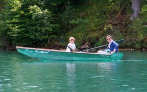 Eine Frau und ein Kind in einem Boot auf dem Wasser. in der Unterkunft Inselhotel Faakersee in Faak am See