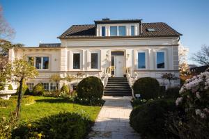 a large white house with a staircase in a yard at Villa Rosengarten in Fehmarn