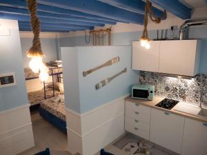 una cocina con armarios blancos y una cama en una habitación en Appartamenti Vale Mare, en Chioggia
