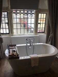 a white bath tub in a room with windows at The Hind Hotel in Wellingborough