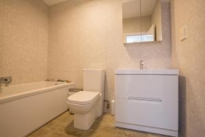 a bathroom with a toilet and a tub and a sink at Invershin -Aldeburgh Coastal Cottages in Thorpeness
