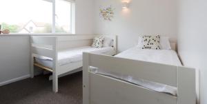 a white bedroom with a bed and a window at Invershin in Thorpeness