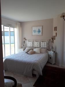 - une chambre dotée d'un grand lit avec des draps et des oreillers blancs dans l'établissement Agréable Maison sur le Bassin d'Arcachon, à Andernos-les-Bains