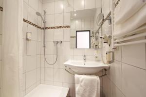 ein weißes Bad mit einem Waschbecken und einer Dusche in der Unterkunft Hotel Karl Noss in Cochem