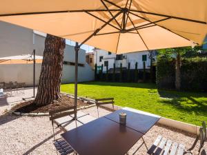 einen Tisch mit einem Regenschirm neben einem Baum in der Unterkunft B&B VILLA TOZZA in Senigallia