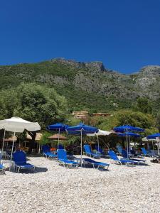 a group of blue chairs and umbrellas on a beach at Villa Dimeli in Barbati