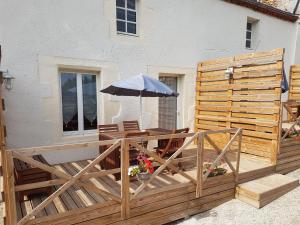 een houten terras met een tafel en een parasol bij Les logis de la maisonnette in Mouchamps