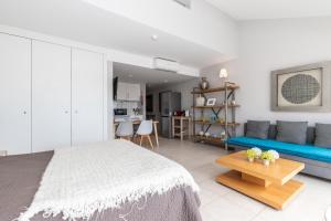 een slaapkamer met een bed en een blauwe bank bij Cabanas Green Apartment Ria Formosa in Cabanas de Tavira +19 foto's