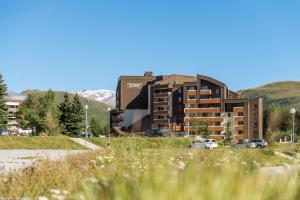 a large building with cars parked in front of it at Résidence Pierre & Vacances Les Bergers in L'Alpe-d'Huez