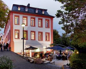 a building with people sitting under umbrellas in front of it at Hotel Lekker in Neumagen-Dhron