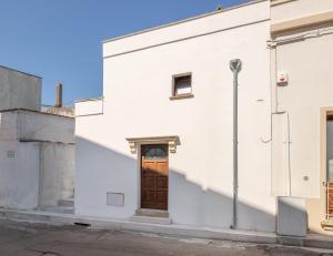 - un bâtiment blanc avec une porte en bois sur le côté dans l'établissement Conte Luxury Apartment by Salento Affitti, à Racale