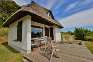 a thatch roof hut with a table and chairs on a deck at Haus am Hügel in Groß Zicker