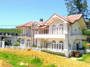 una casa con una valla blanca en Maples Holiday Resort, en Nuwara Eliya