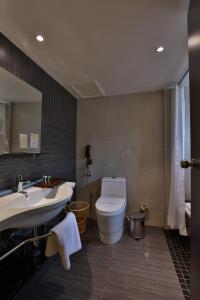 a bathroom with a white toilet and a sink at Hotel Luminara in Cochin