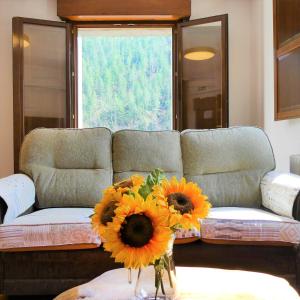 ein Wohnzimmer mit einem Sofa mit Sonnenblumen auf dem Tisch in der Unterkunft Casa rural Bidezarra a los pies de la selva de Irati in Ochagavía