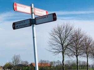 un panneau de rue comportant plusieurs panneaux de rue sur un poteau dans l'établissement Slapen bij de Zeeuwse Lala, à IJzendijke