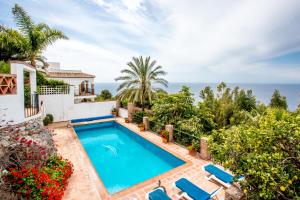 una piscina frente a una casa con el océano en el fondo en Casa Vicente, en La Herradura