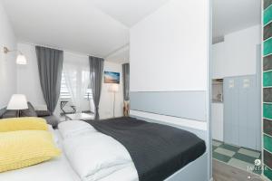 コウォブジェクにあるJantar Apartamenty - Promenada Kołobrzegのベッドルーム(白いベッド1台、黄色い枕付)