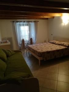ein Schlafzimmer mit einem Bett, einem Sofa und einem Fenster in der Unterkunft Appartamento" Le Bourg 61" VDA CIR 0208 in Aosta