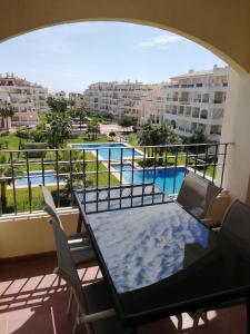 balcón con mesa, sillas y piscina en Entre el Mar y el Golf. Wifi privado., en Roquetas de Mar