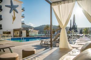 un complejo con piscina y sillas y un hotel en Hotel Eden Soller, en Puerto de Sóller