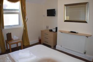 a bedroom with a bed and a dresser and a mirror at Cedar Lodge in Llandudno +79 photos