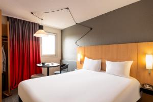 セルジーにあるイビス セルジー ポントワーズ ル ポールの大きなベッドとテーブルが備わるホテルルームです。