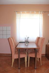 a dining room table with chairs and a window at Apartments Isabela in Baška