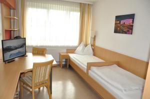 a hotel room with two beds and a desk and a tv at Kolpinghaus Linz in Linz