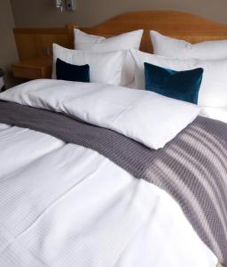 un grande letto con lenzuola bianche e cuscini blu di Hotel Tari a Würzburg