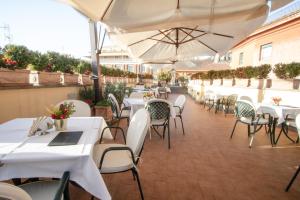a restaurant with white tables and chairs and umbrellas at Hosianum Palace in Rome