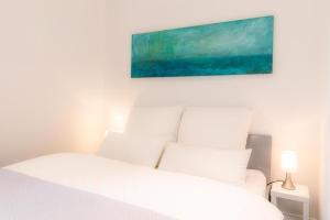 a bedroom with a white bed with a painting above it at Apartment 229 in Dortmund