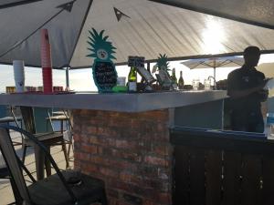 a man standing behind a bar with bottles of alcohol at Pili Pili Beach Cabanas in Sedgefield