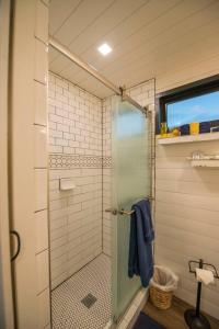 a shower with a glass door in a bathroom at Elegant Container Tiny House Yellow & Blue in Waco