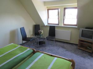 a bedroom with two beds and a tv and chairs at Ferienwohnung Rogge (Stendal) in Wittenmoor