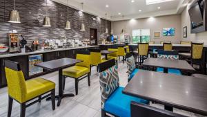 a restaurant with tables and yellow and blue chairs at Best Western Plus Waller Hotel in Waller